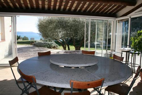 - une grande table sur la terrasse entourée de chaises dans l'établissement Grand Mas en Provence avec piscine, à Istres