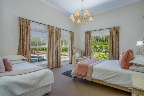 a bedroom with two beds and a large window at Franschhoek Rose Cottages in Franschhoek
