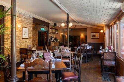 a restaurant with wooden tables and chairs and a brick wall at Crown Hotel in Chertsey
