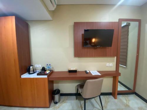 a room with a desk with a tv on the wall at Grand Avira Hotel in Batu Merah