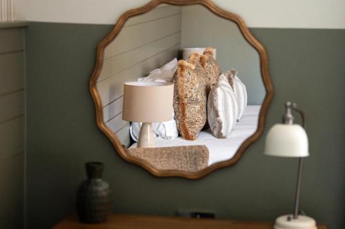 a mirror on a wall with a lamp and bread at Crown Hotel in Chertsey