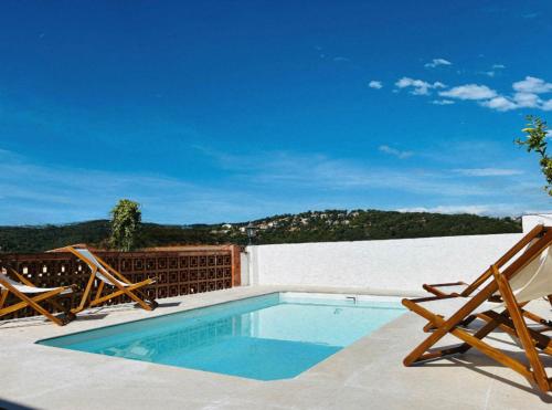a swimming pool with two chairs and a table at Villa Mediterranea Tossa in Tossa de Mar