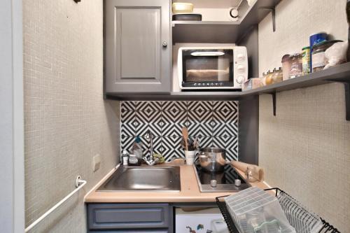 une petite cuisine avec un évier et un micro-ondes dans l'établissement Charmant studio, central, à Paris