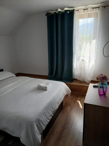 a bedroom with a bed with a blue curtain and a window at Casa Loredana in Cîrţişoara