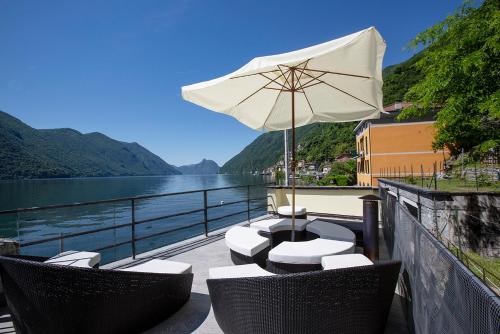 a patio with chairs and an umbrella and water at La Sentinella - Lake View & Panoramic Terrace in Valsolda