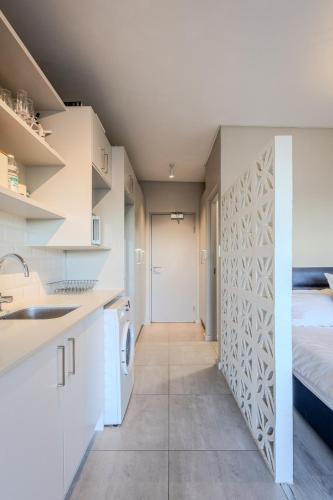 a kitchen with white cabinets and a bed in a room at Stylish Table View Studio Fully Equipped in Cape Town