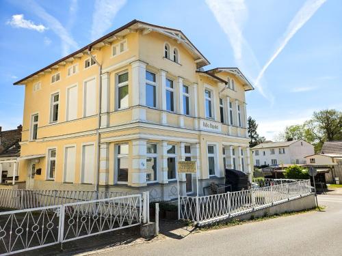 a yellow building with a fence in front of it at Villa Utpatel Whg 01 in Ahlbeck