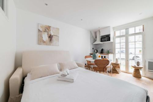 a white bedroom with a bed and a dining room at Escapade urbaine Appartement Mairie des lilas in Les Lilas