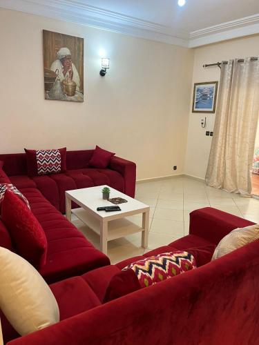 a living room with two red couches and a table at إقامات أهلا قرب مرجان طريق الرباط in Oulad Akkou