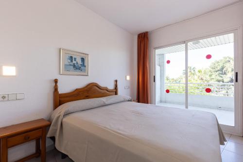 a white bedroom with a bed and a window at Rentalmar Royal in Salou