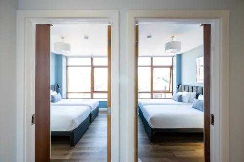 two beds in a room with two windows at Staycity Aparthotels Dublin Augustine in Dublin