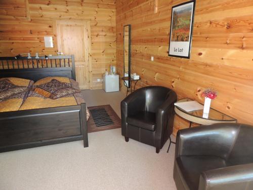 1 dormitorio con 1 cama y 1 silla en una cabaña en Chambre d'hôte L'Arrivée, en Autoire