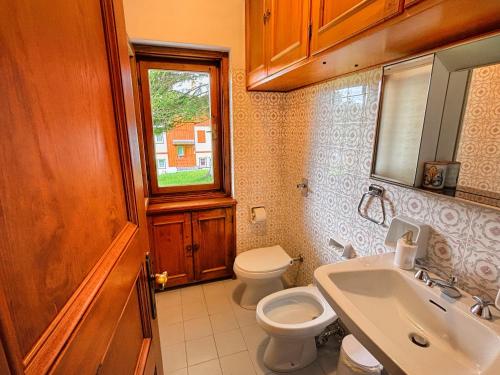 a bathroom with a toilet and a sink and a window at Large Central Flat, 5min to Sky Slopes, Garage in Cortina dʼAmpezzo