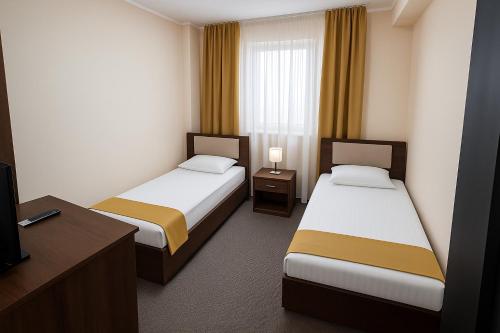 a hotel room with two beds and a desk at Pensiunea Luca in Baile Felix