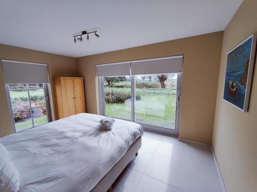 a bedroom with a large bed and a large window at Het Weiland Villa Jersey in Damme