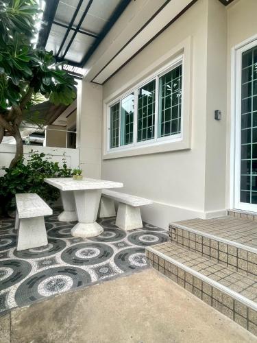 a patio with a table and benches in front of a building at Private Pool Getaway - Baan Hug Ubon Warinchamrap in Ubon Ratchathani