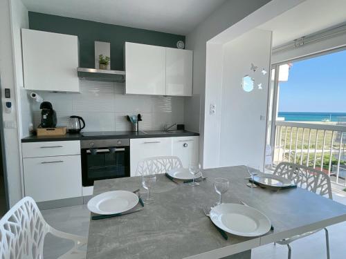 une cuisine avec une table avec des assiettes et des verres dessus dans l'établissement évasion méditerranéenne - vue mer - plage, au Barcarès