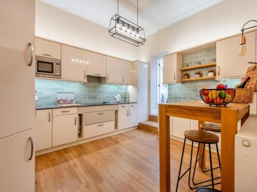 a kitchen with white cabinets and a wooden table at The Annex at Merley Mews in Poole