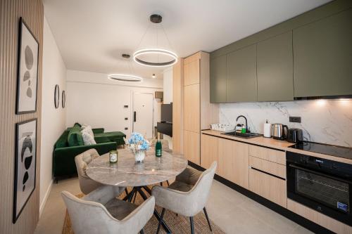a kitchen and a dining room with a table and chairs at Beatrice Apartment in Odyssey Pool & Spa-parking in Mamaia