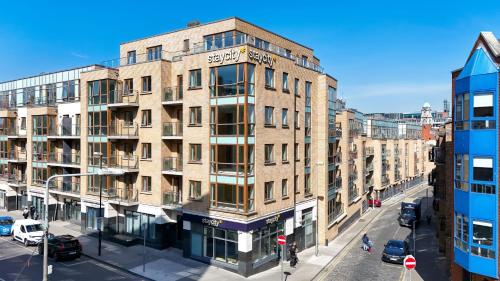 a large brick building on a city street with cars at Staycity Aparthotels Dublin Augustine in Dublin