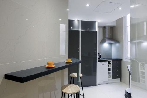 une cuisine avec un comptoir et deux tabourets dans l'établissement 13 Boulevard Carnot by Halldis, à Cannes