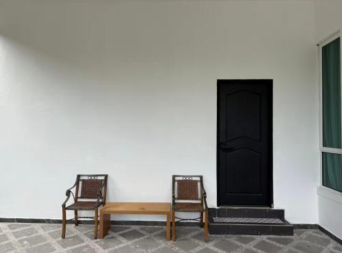 two chairs and a wooden bench next to a door at Cozy Nest Panji in Kota Bharu