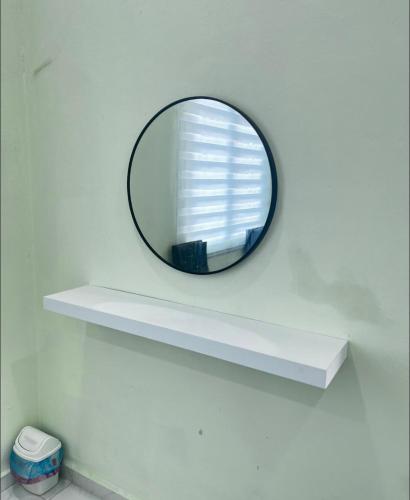 a round mirror on a shelf in a bathroom at Cozy Nest Panji in Kota Bharu
