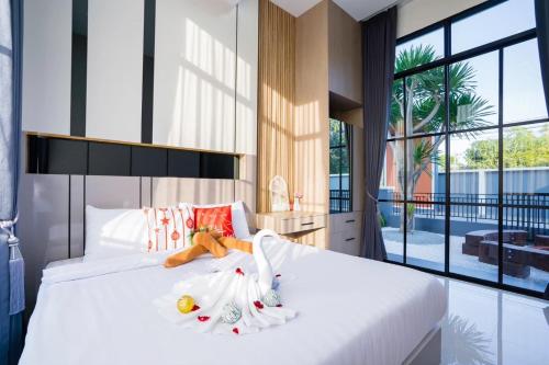 - une chambre dotée d'un lit blanc avec un animal rembourré dans l'établissement Mavia fun poolvilla pattaya, à Nong Prue