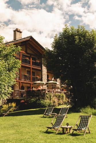 a group of lawn chairs in front of a house at Auberge de La Maison in Courmayeur