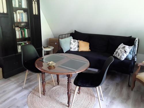 a living room with a black couch and a table at Un week-end à la campagne in Pont-Audemer
