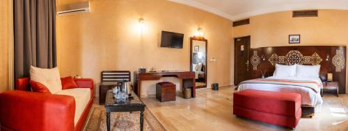 a hotel room with a bed and a desk and chairs at Palais Du Desert Hotel & Spa in Erfoud