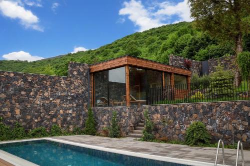 a house with a stone wall and a swimming pool at Dilijani Tun Hotel & Restaurant in Dilijan