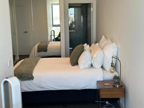 a bedroom with a bed with white pillows and a mirror at Rise to the top! in Melbourne