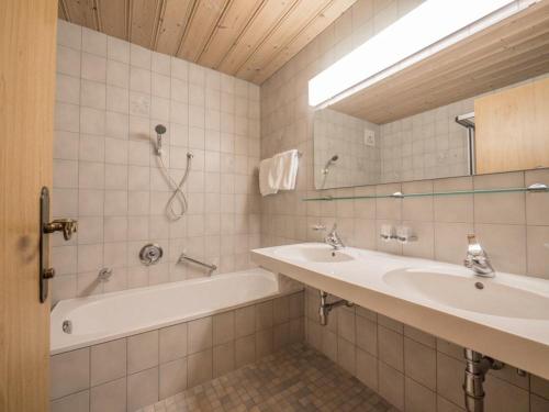 a bathroom with a tub and two sinks and a bath tub at Ferienwohnungen Egger in Fügen