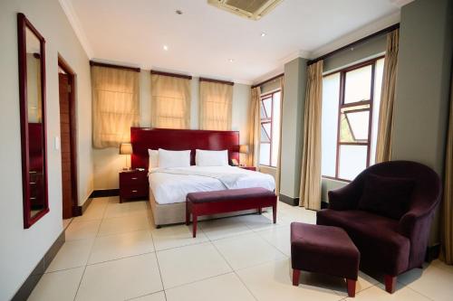 a hotel room with a bed and a chair at Tamboti Guest Lodge in Pretoria