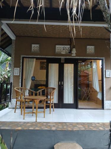 a patio with a table and chairs in front of a house at Pondok Salacca#bamboohouse# in Candidasa
