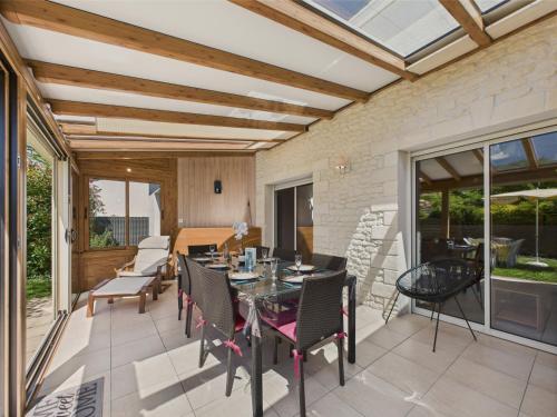 une salle à manger avec une table et des chaises sur un patio dans l'établissement Maison pour 8 - 5min de la plage - jardin & véranda, à Longeville-sur-Mer