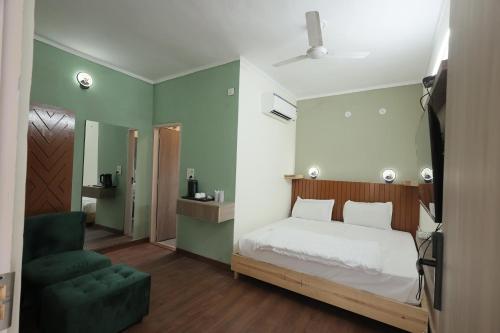 a bedroom with a bed and a green chair at Staybook The Rudveda Resort - Free High Tea near Pool Area in Rāmnagar