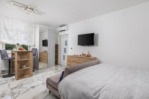 a white bedroom with a bed and a television at Vila Lux 3 in Rijeka