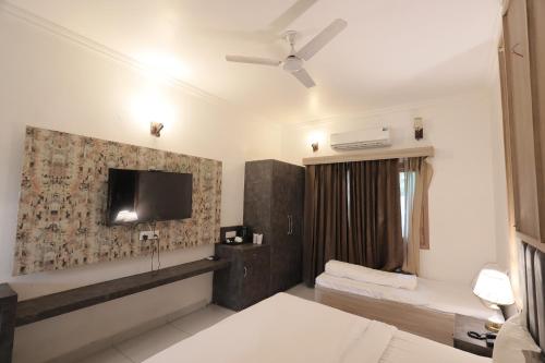 a hotel room with a television and a bed at Staybook The Rudveda Resort - Free High Tea near Pool Area in Rāmnagar