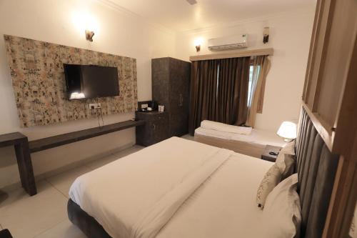 a hotel room with a bed and a flat screen tv at Staybook The Rudveda Resort - Free High Tea near Pool Area in Rāmnagar