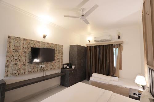 a hotel room with a tv and a bedroom at Staybook The Rudveda Resort - Free High Tea near Pool Area in Rāmnagar