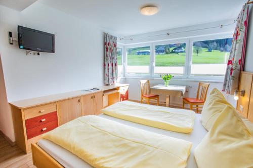 a bedroom with two beds and a table and a television at Bergerhof in Ramsau am Dachstein