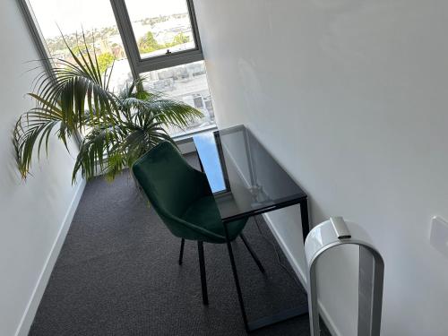 a desk with a green chair in a room with a window at Rise to the top! in Melbourne