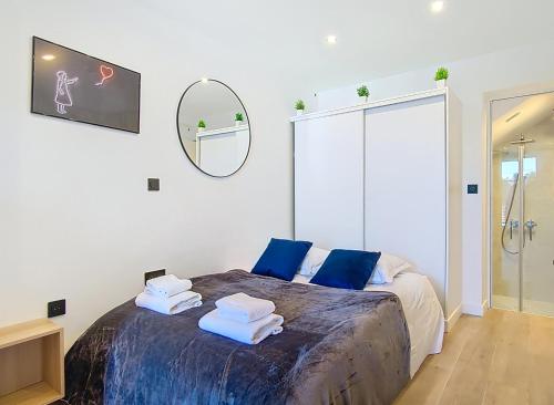 une chambre avec un lit avec des oreillers bleus et un miroir dans l'établissement Suite Street Art - Appartement central, à Argenteuil