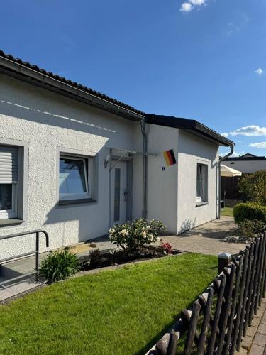 a white house with a fence in front of it at Ferienhaus Hunsrückliebe mit privater Außensauna in Liederbach