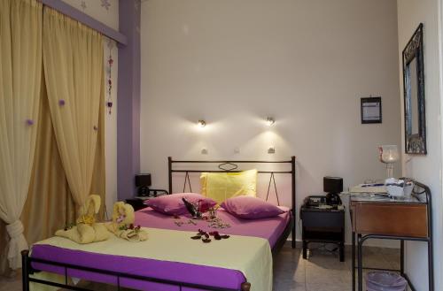 a bedroom with a bed with pink pillows at Hotel George in Kalamata
