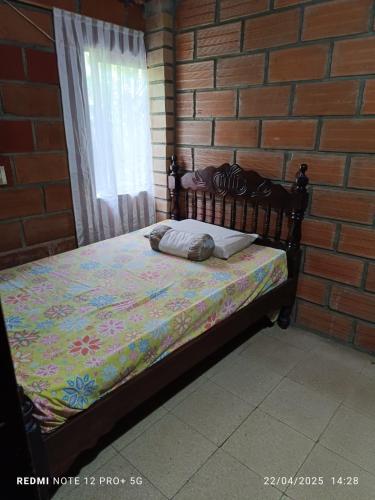 a bed in a room with a brick wall at Finca Arcanos Celeste in Barbosa