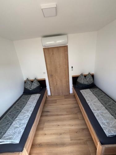 two beds in a room with a door at Resort Winklfeld 6a in Oberndorf bei Schwanenstadt