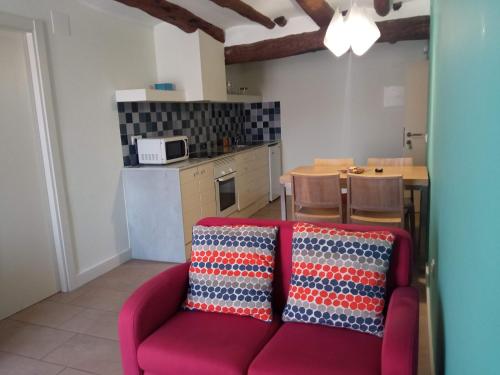 a living room with a red couch and a kitchen at Apartamentos Bergantes in Ortells